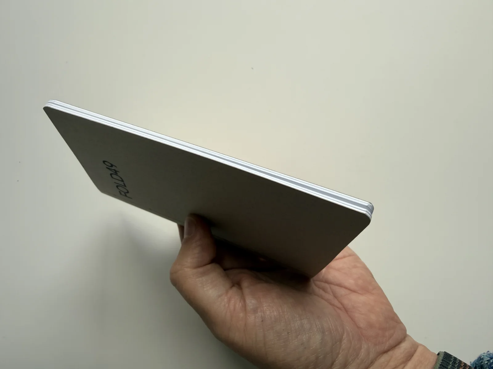FOLD49 notebook held at an angle, showing its Solid Core cover and white page edges